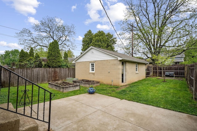 back of house with a vegetable garden, a patio area, and concrete block siding