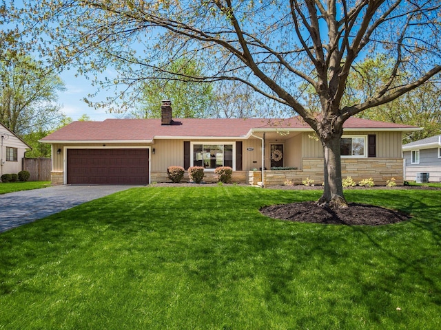 ranch-style home with an attached garage, a front lawn, driveway, and a chimney