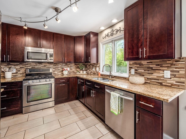 kitchen with a sink, appliances with stainless steel finishes, decorative backsplash, and light stone counters