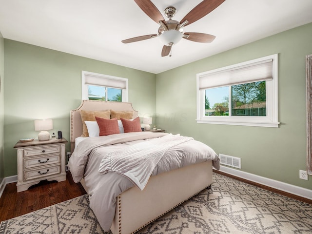 bedroom featuring baseboards, multiple windows, wood finished floors, and visible vents