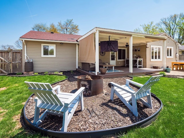 back of property featuring a lawn, fence, a fire pit, and a ceiling fan