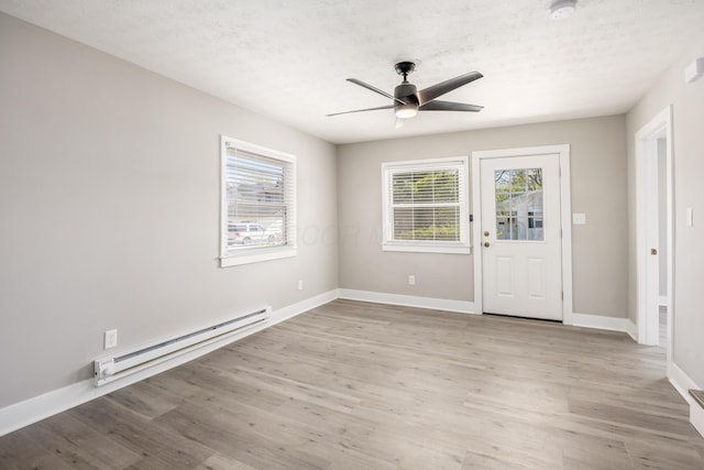 116 W S Ave, Plain City, OH 43064 - interior space featuring a baseboard heating unit, light wood-style floors, baseboards, a ceiling fan, and a textured ceiling