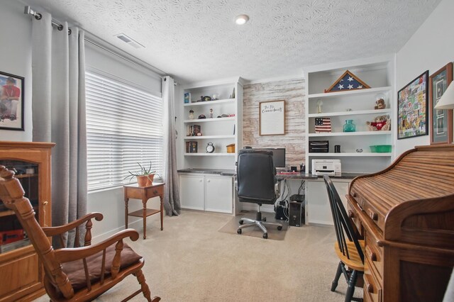 office area featuring visible vents, a textured ceiling, carpet floors, and built in shelves