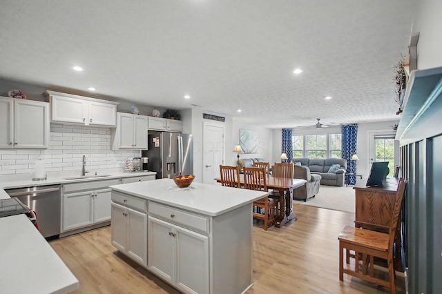 kitchen featuring light wood-type flooring, light countertops, tasteful backsplash, a sink, and stainless steel appliances