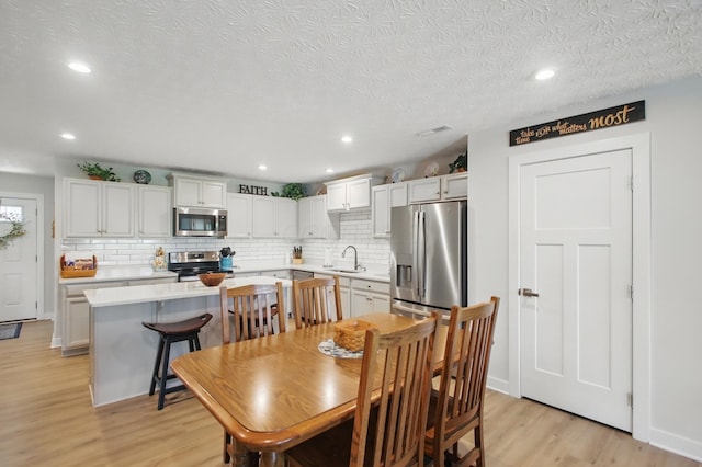 dining room featuring a textured ceiling, recessed lighting, light wood-style flooring, and visible vents