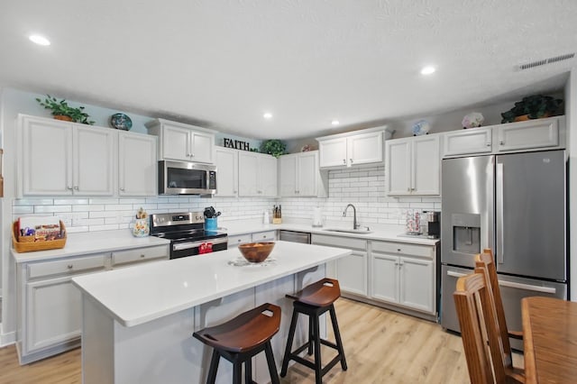kitchen with light countertops, tasteful backsplash, stainless steel appliances, and light wood-type flooring