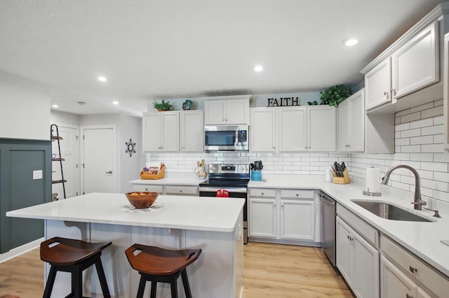 kitchen with appliances with stainless steel finishes, a breakfast bar, a sink, a center island, and decorative backsplash