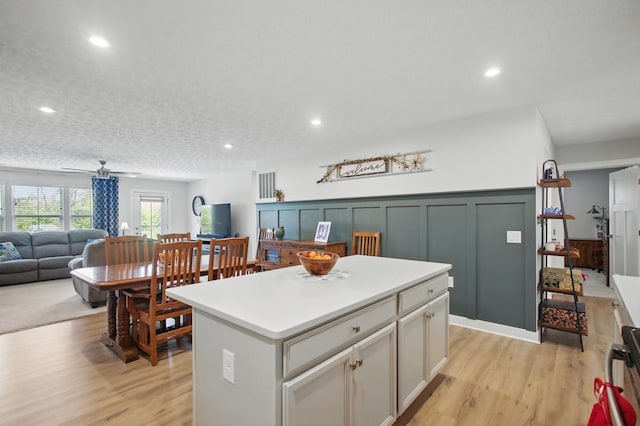kitchen featuring a kitchen island, a ceiling fan, open floor plan, and light wood finished floors