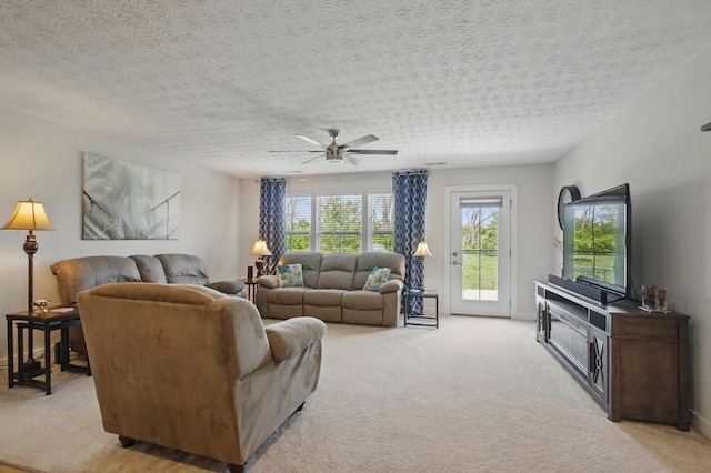 living room with ceiling fan, a textured ceiling, and light colored carpet