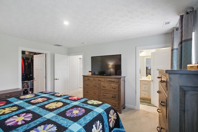 bedroom with ensuite bathroom, recessed lighting, a textured ceiling, and light colored carpet