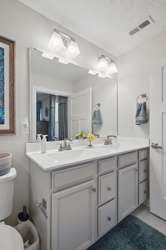 bathroom featuring double vanity, toilet, visible vents, and a sink