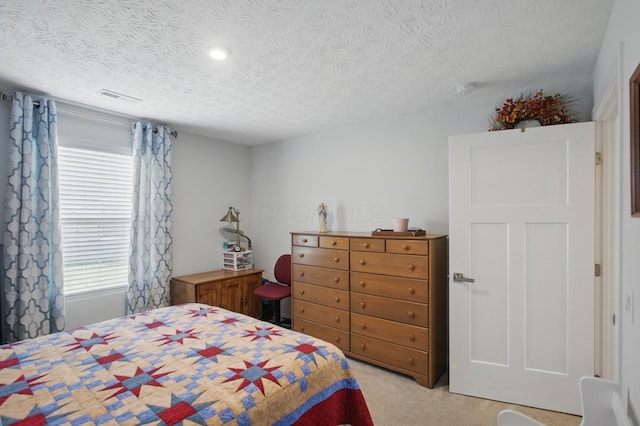 bedroom with visible vents, a textured ceiling, and carpet
