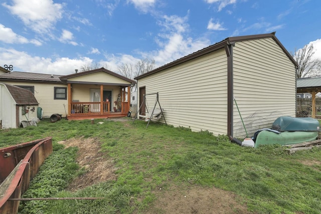 rear view of property featuring an outdoor structure, a lawn, fence, and a shed