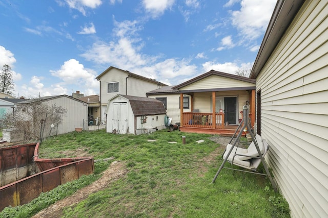 back of property featuring a lawn, a storage shed, fence, and an outbuilding