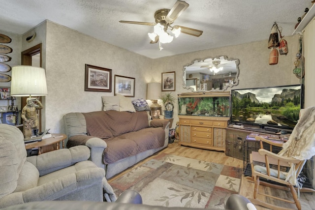 living room featuring wood finished floors, a ceiling fan, and a textured ceiling