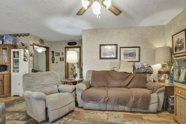 living room with a ceiling fan, wood finished floors, and a textured ceiling