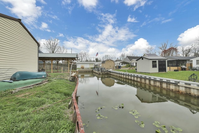 view of dock with a lawn, a water view, and fence