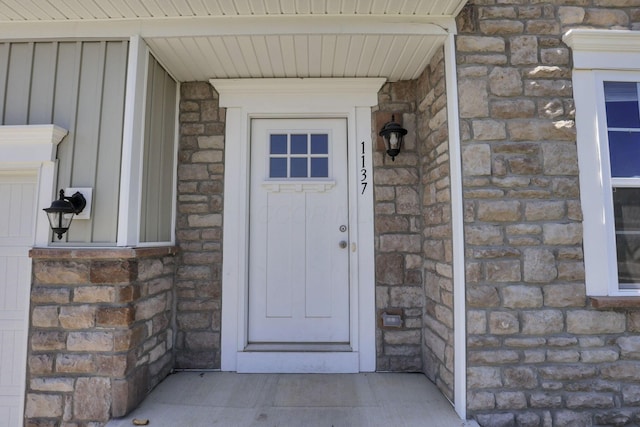doorway to property with board and batten siding and stone siding