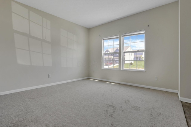 spare room featuring carpet floors and baseboards