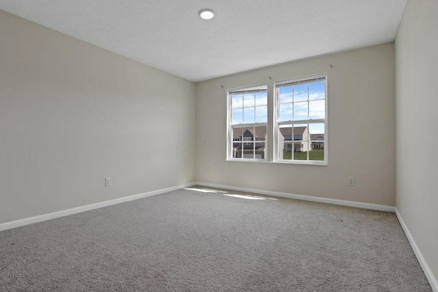 carpeted spare room featuring baseboards
