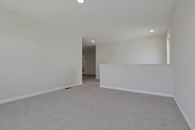 spare room with recessed lighting, carpet, baseboards, and visible vents