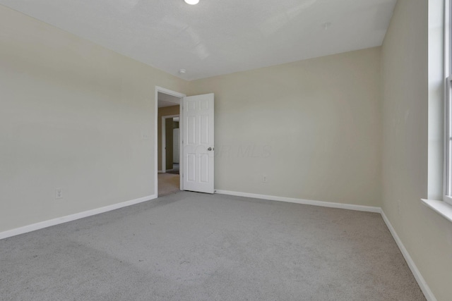 spare room featuring carpet floors and baseboards