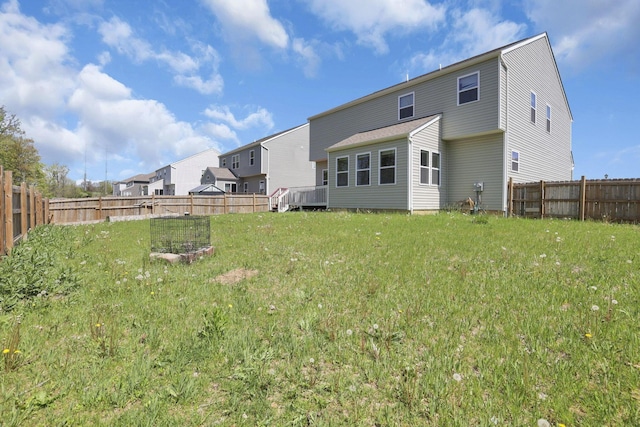 rear view of house with a fenced backyard and a lawn