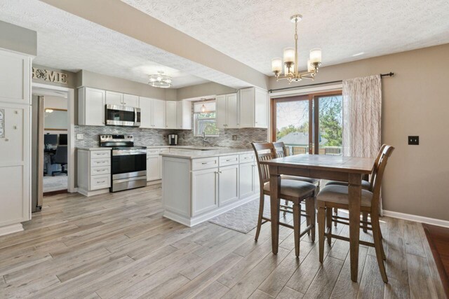 81 Highmeadows Cir, Powell, OH 43065 - kitchen featuring light wood-style flooring, stainless steel appliances, decorative backsplash, and a notable chandelier
