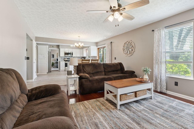 81 Highmeadows Cir, Powell, OH 43065 - living area with a textured ceiling, baseboards, light wood-style flooring, and ceiling fan with notable chandelier