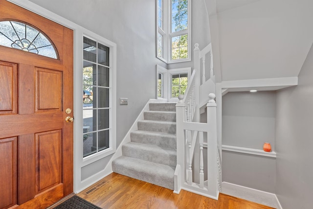 660 Woods Hollow Ln, Powell, OH 43065 - entryway with visible vents, baseboards, a towering ceiling, wood finished floors, and stairs