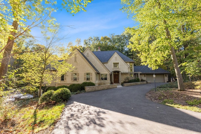 660 Woods Hollow Ln, Powell, OH 43065 - french country home with a chimney, stucco siding, driveway, stone siding, and an attached garage