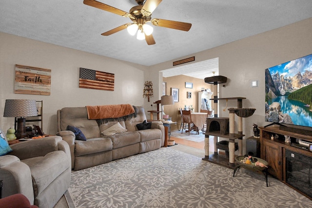 living area featuring ceiling fan and a textured ceiling