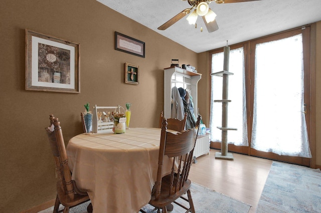 dining area featuring a textured ceiling, light wood finished floors, ceiling fan, and lofted ceiling