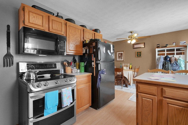 kitchen with ceiling fan, light wood-type flooring, light countertops, a textured ceiling, and black appliances