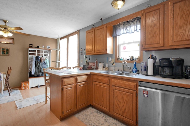 kitchen featuring a sink, light countertops, stainless steel dishwasher, and a peninsula