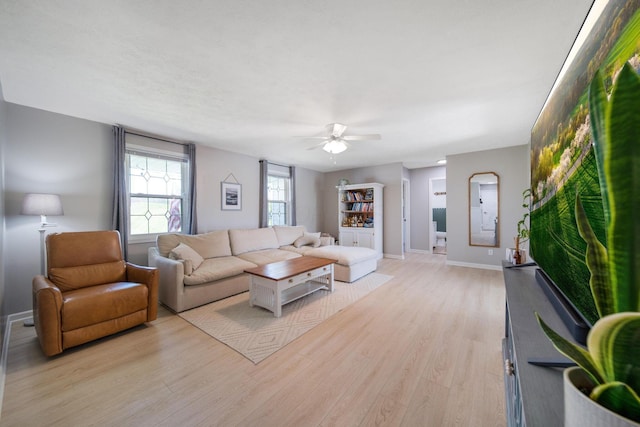 living area featuring a ceiling fan, light wood-style flooring, and baseboards