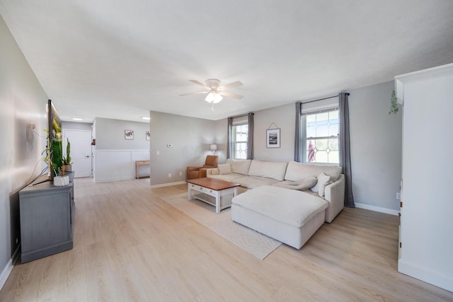 living room featuring baseboards, a ceiling fan, and light wood-style floors