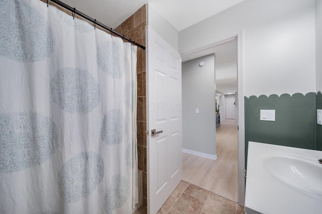 full bathroom with baseboards, a shower with shower curtain, and a sink