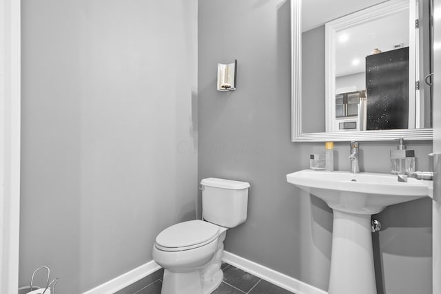 half bathroom with baseboards, tile patterned flooring, and toilet
