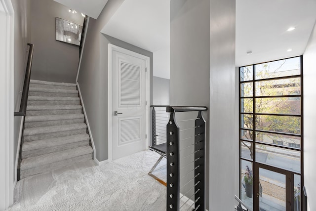staircase featuring carpet floors, baseboards, floor to ceiling windows, and recessed lighting