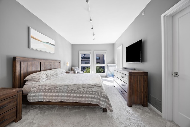 bedroom featuring rail lighting and light colored carpet