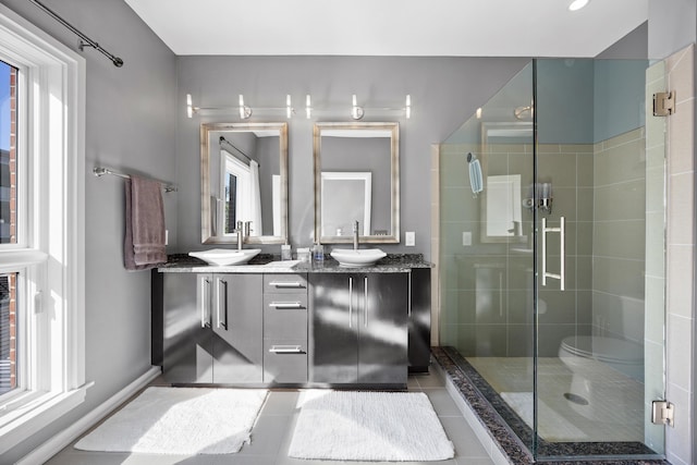 bathroom with a sink, tile patterned flooring, a shower stall, and double vanity