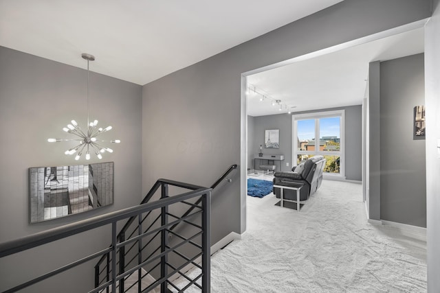 hallway featuring baseboards, an upstairs landing, carpet flooring, and a chandelier