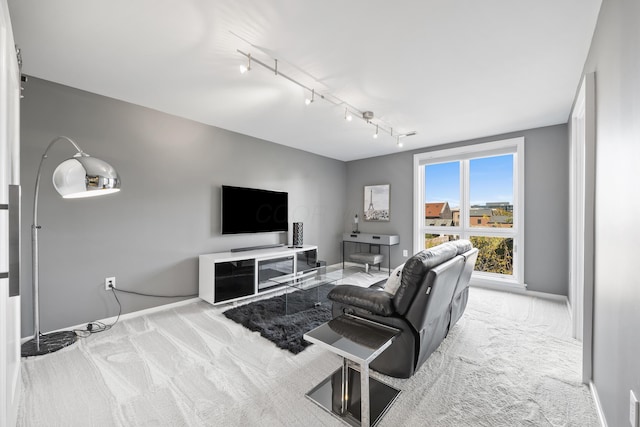 carpeted living area featuring baseboards and rail lighting