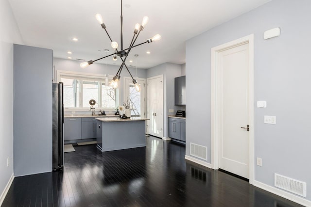 kitchen with gray cabinets, a kitchen island, a chandelier, and visible vents