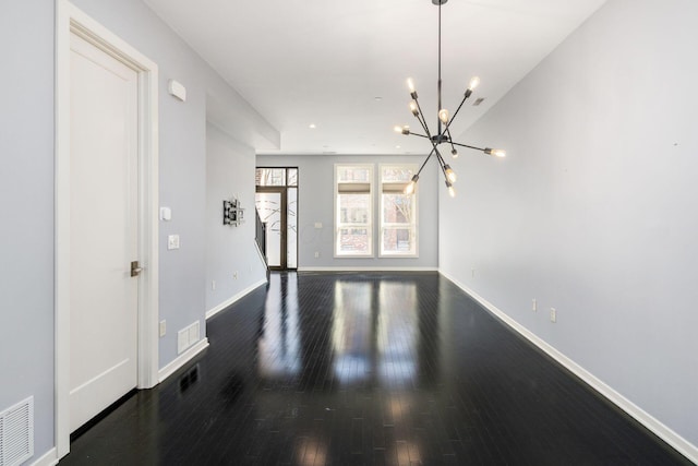 interior space with baseboards, visible vents, wood finished floors, and a chandelier