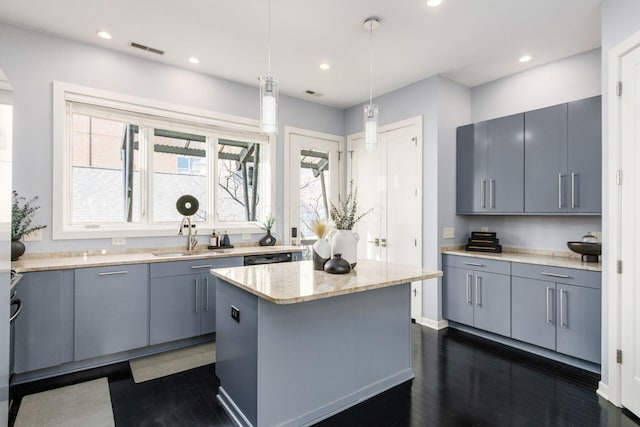 kitchen featuring a kitchen island, gray cabinets, visible vents, and a sink
