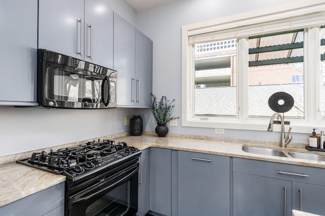 kitchen featuring a sink, gray cabinets, black appliances, and light stone counters