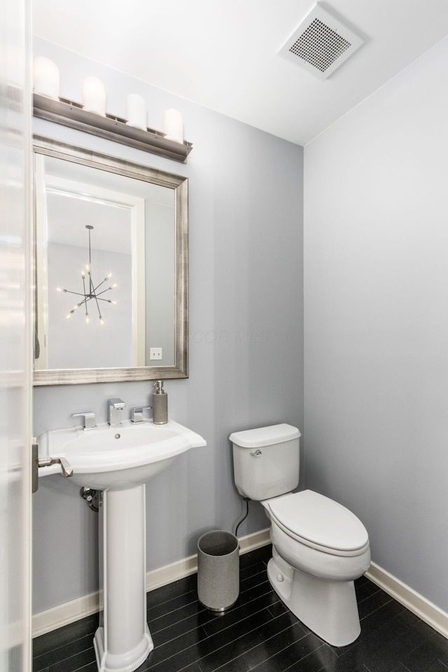 half bath featuring visible vents, baseboards, wood finished floors, and toilet