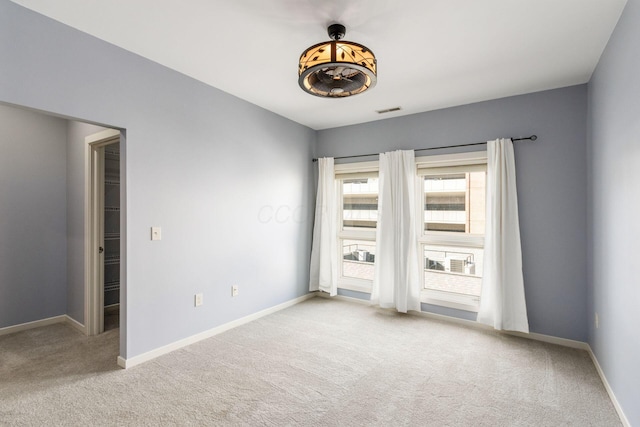 unfurnished room with baseboards, carpet, and visible vents
